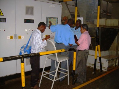 Auditors reviewing readings at an electrical control panel with plant staff
